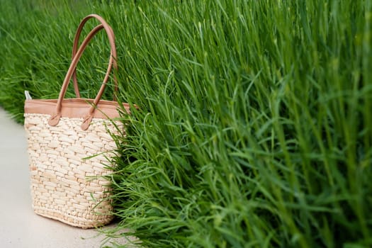 front view closeup of empty brown wicker bag with green grass in the background