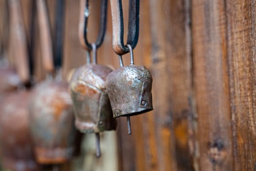 perspective view closeup of metal rusted cowbells with leather collar isolated on brown wooden background