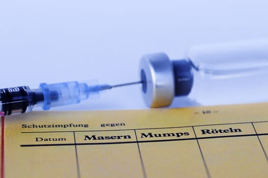 Vaccination against measles, mumps and rubella with vaccination card, syringe and vaccine