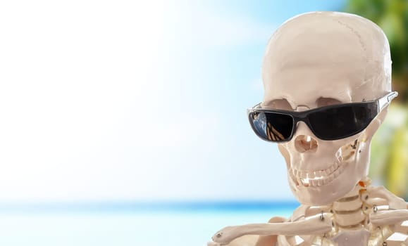 The human skeleton with glasses on a tropical beach