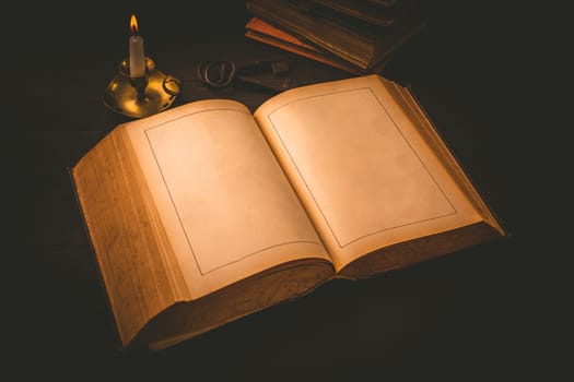 Old antique book with empty pages and candle in vintage style on black background
