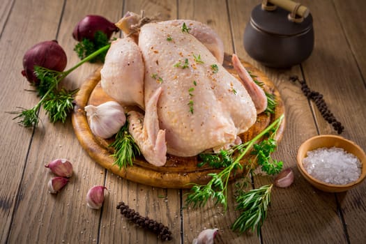 Raw chicken with onion, garlic and herbs with spices ready for cooking on wooden table
