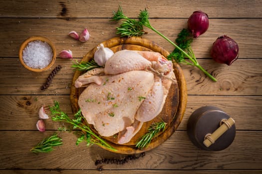 Raw chicken with onion, garlic and herbs with spices ready for cooking on wooden table