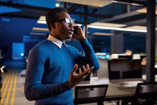 Manager talking by phone, office lifestyle. Male person at the table, dark business center interior on background, modern workplace