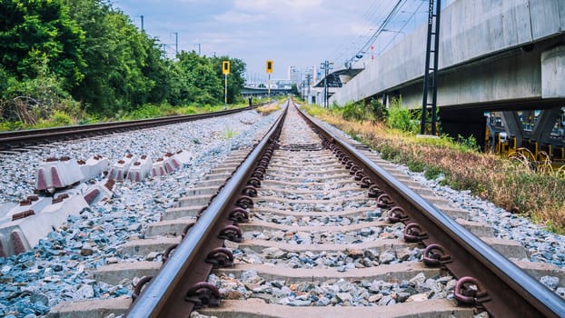 Empty railway with no train and people, selective focus and vintage style. Railroad and beautiful sky at sunset in summer. Rural industrial landscape with railway station