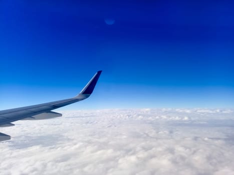 Wing of the plane on blue sky background. Airplane Wing in Flight from window, blue sky. Travel concept idea.