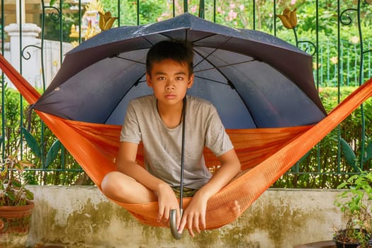 Children under the umbrella on the hammock when it rains.