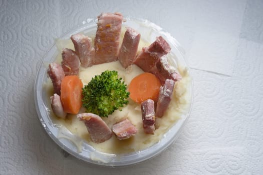 Plastic ready meal tub, containing mashed white potato, vegetables and gammon. Gammon sliced into thin strips and arranged in a circle. Artistic food