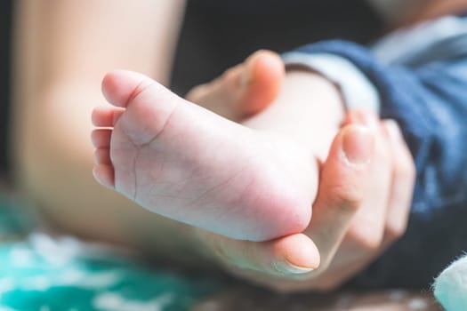 Close up of mother’s hands, holding newborn baby feet.