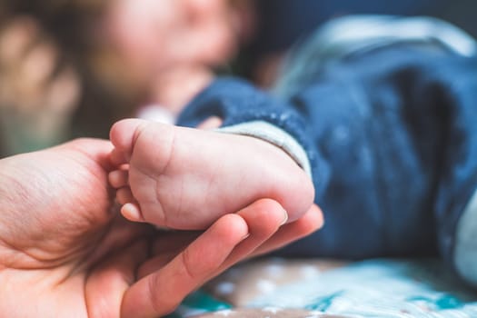 Close up of mother’s hands, holding newborn baby feet.