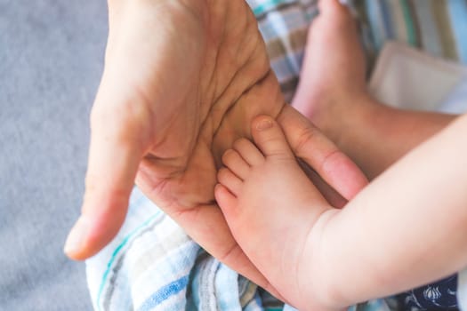 Close up of mother’s hands, holding newborn baby feet.