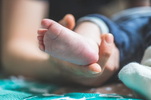 Close up of mother’s hands, holding newborn baby feet.