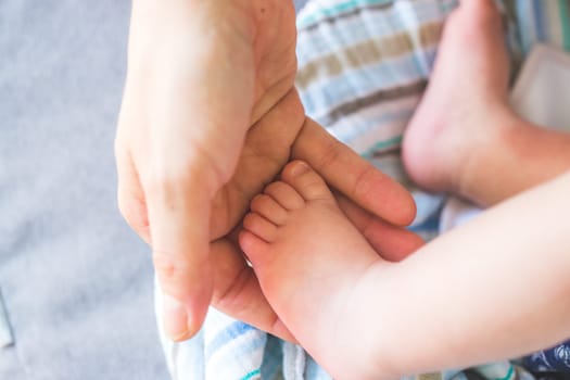 Close up of mother’s hands, holding newborn baby feet.
