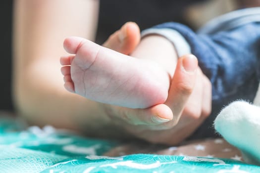 Close up of mother’s hands, holding newborn baby feet.