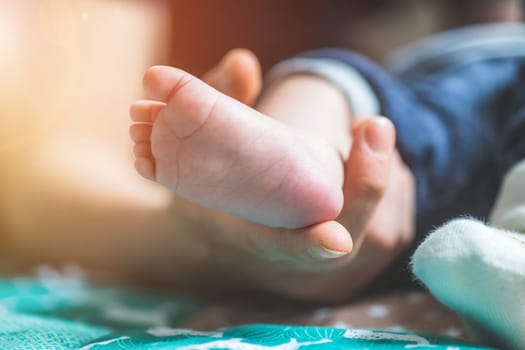 Close up of mother’s hands, holding newborn baby feet.
