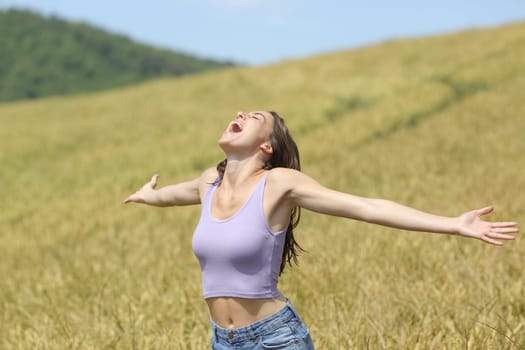 Excited woman screaming in a wheat field