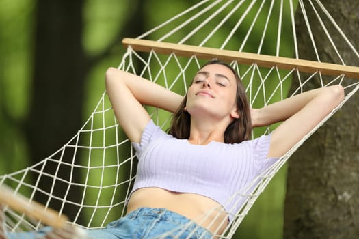 Relaxed woman on summer resting on rope hammock
