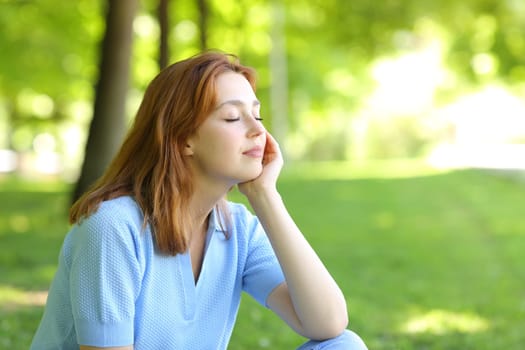Relaxed woman sitting in a park with closed eyes