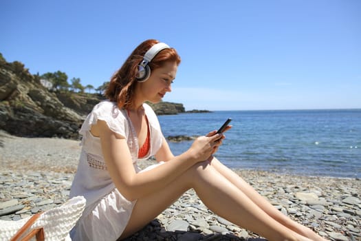 Woman on the beach checking music on smartphone