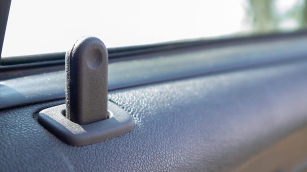 Close the lock button for the interior door of the vehicle. Door lock button inside the car interior close-up