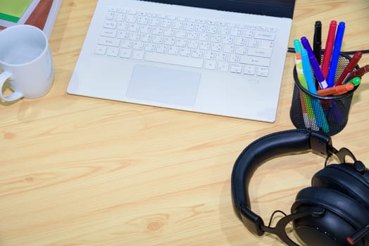 Top view of a workplace with laptop computer pen headphones book and cup with blank space on the desktop and online learning tools, Concept remote study and work from a home education background