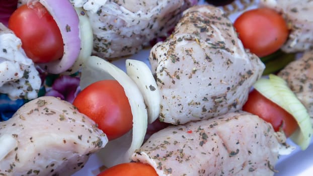 Raw pork shashlik with spices, cherry tomatoes and onions on skewers ready to cook. Fresh raw kebab