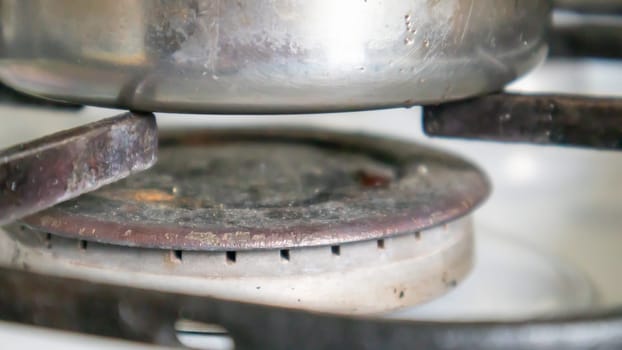 Dirty gas stove in the kitchen for cooking with vegetable oil stains and burnt food debris on the surface, close-up. Selective focus. Grease-covered gas hob in the kitchen