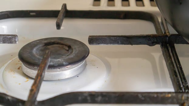 Dirty gas stove in the kitchen for cooking with vegetable oil stains and burnt food debris on the surface, close-up. Selective focus. Grease-covered gas hob in the kitchen
