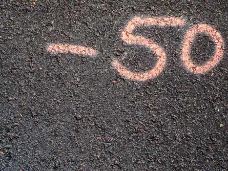 Top view of number minus 50 written on asphalt in pink color.