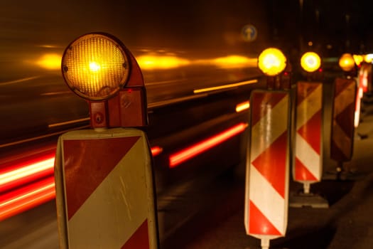 Roadworks with warning lights and trails of a car and lorry