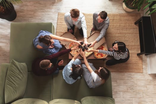 A pizza party, a group of friends chatting and happily eating pizza at the table and drinking sweet soda water. Top view from the second floor. High quality photo