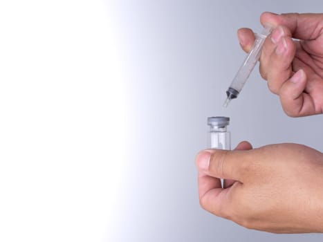 A man's hand is holding a bottle of vaccine and a sling for injection.