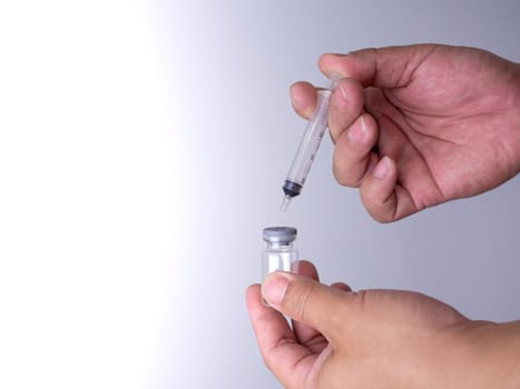 A man's hand is holding a bottle of vaccine and a sling for injection.