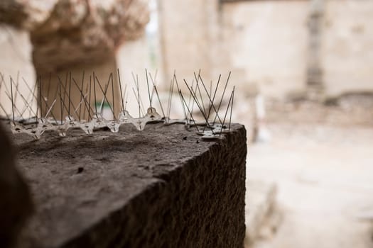 Repellent metal spikes installed over cornice of historic building. Bird Control concept for Architectural Heritage