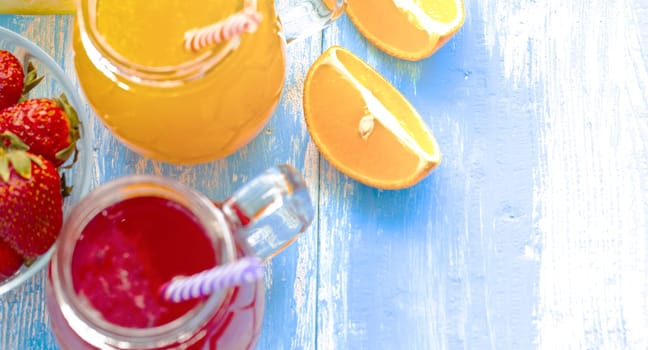 The Orange and strawberry juice in glass on old wooden blue table