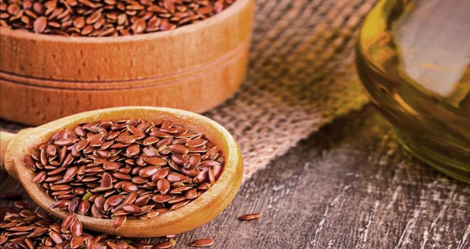 The Brown flax seeds and flaxseed oil on a wooden table