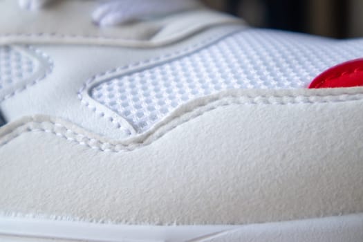 White color mesh fabric on a part of sports shoes. Running shoe net. Sportswear textured lattice. Textile texture background. Detail of a white sneaker in fabric with laces. Fragment of sports shoes
