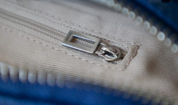Natural or artificial leather texture. Fragment of a blue bag with a zipper and stitching. Zipper or clasp bag design element. Bovine skin texture with snake. Macro photo, selective focus
