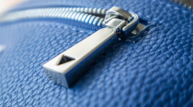 Natural or artificial leather texture. Fragment of a blue bag with a zipper and stitching. Zipper or clasp bag design element. Bovine skin texture with snake. Macro photo, selective focus
