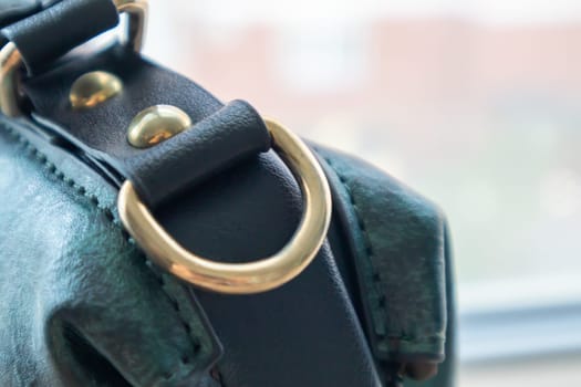 Metal gold loop oval ring attached to a leather bag. Selective focus. Part for a secure connection between two objects. Sewing accessories in the form of a ring for sewing bags, glossy