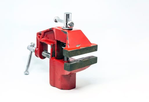 close-up view of a red steel bench vise isolated on a white background. Working tool. Table vise.