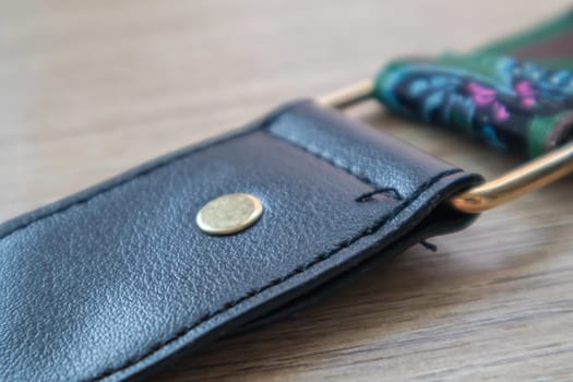 Detail of a fashionable black leather handbag close-up. Fashion concept. Details of a belt, metal buckle, fastener, sewing threads, macro photography. Stylish female accessory