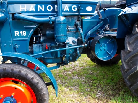 Nesselwang, Germany - July 23, 2020: Side view of a blue perfectly restored HANOMAG tractor away from a veteran tractor.