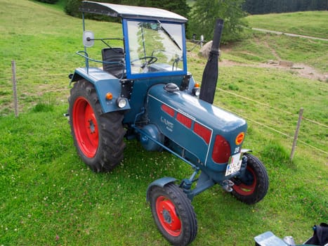 Nesselwang, Germany - July 23, 2020: Side view of a blue perfectly restored LANZ tractor away from a veteran tractor right on a green meadow.