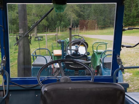 Nesselwang, Germany - July 23, 2020: Interior view with a view through the windshield of a green restored LANZ tractor aside from a veteran tractor.
