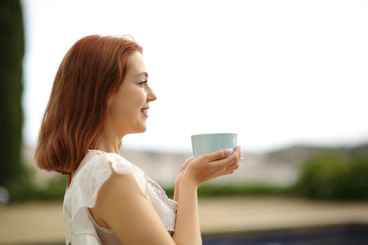 Happy woman drinking coffee contemplating in a garden