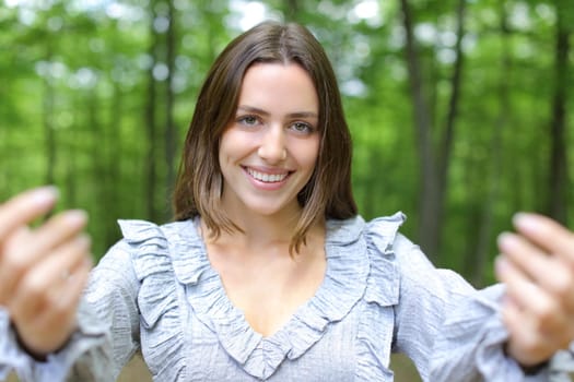 Happy woman saying come here beckoning in a park