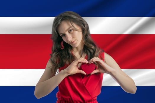 Love Costa Rica A girl holds a heart on her chest in her hands against the background of the flag of Costa Rica
