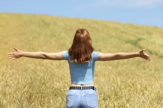 Woman outstretching arms in a wheat field