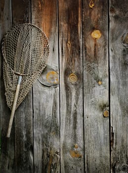 An old fishing net hanging on rustic wooden wall